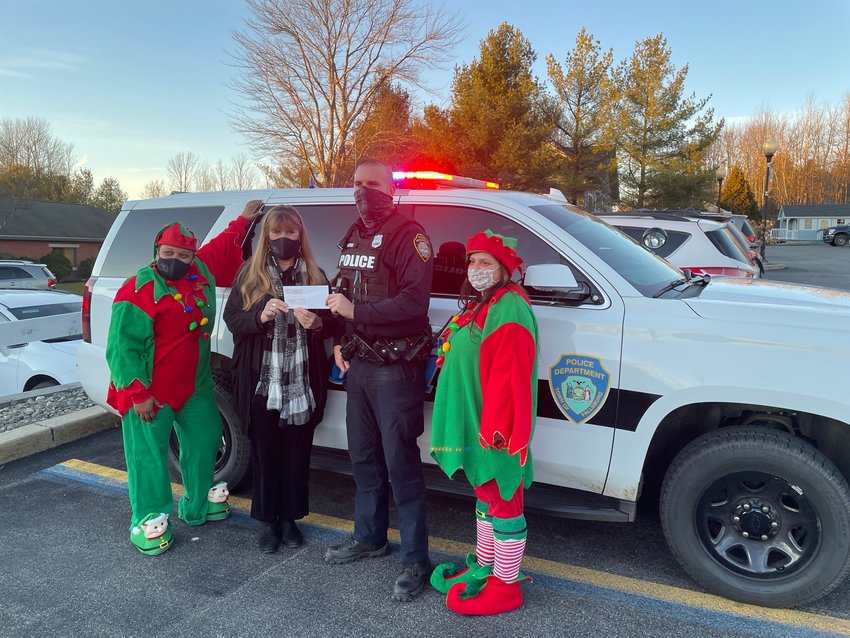 New Hope Community CEO Debbie McGinness presents Asprea, a Fallsburg police officer, with a holiday donation to the Police Benevolent Association.